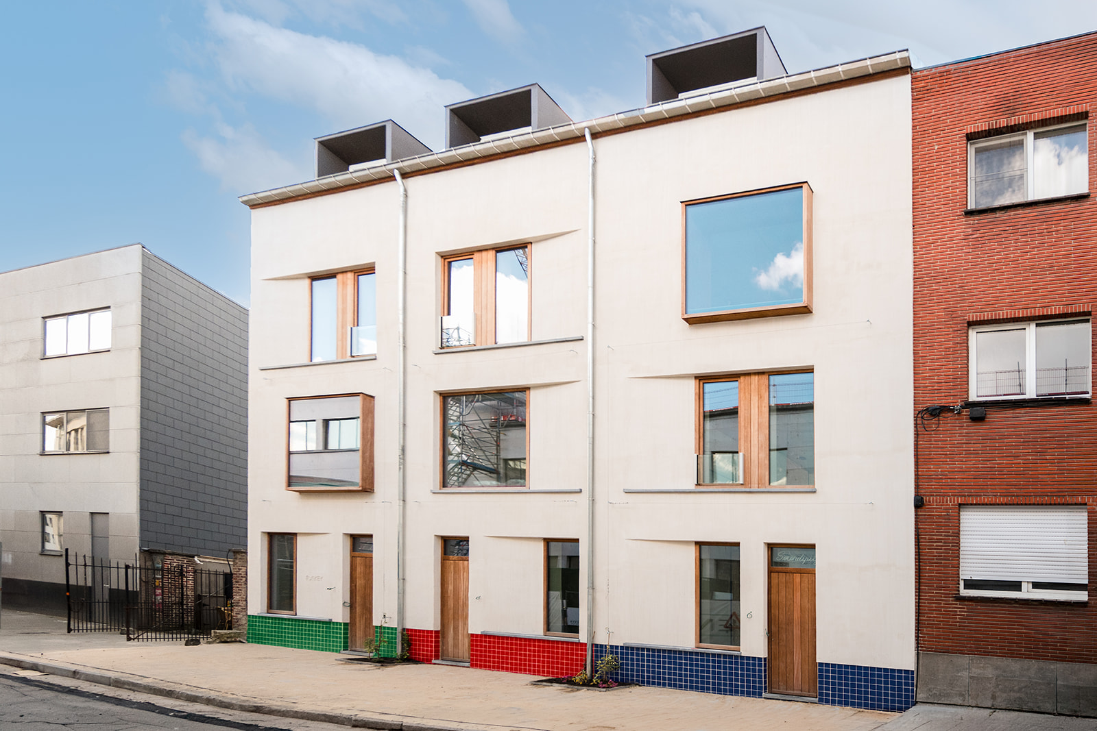 Exterior facade of the three Funkey townhouses with green, red and blue tiled bases